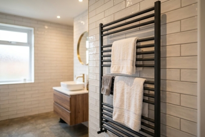 Image showing a black heated towel rail fitted to a tiled wall in a bathroom | Article Image